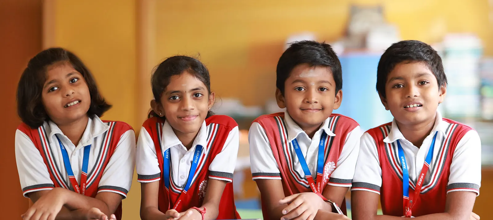 Four smiling Akshara students in uniform