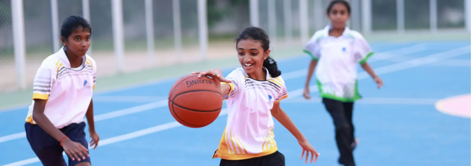 Students playing basketball on the Akshara court